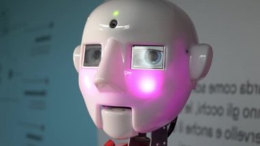 Robot duygularını gösteriyor. Yapay Zeka. Modern robotik. Robot insanlara bakıp gülümsüyor. Robotun gözleri. Sayborg. Robot kameraya bir insana bakıyor. Akıllı bilgisayar. Geleceğe. Çocuklar için harika bir oyuncak..
