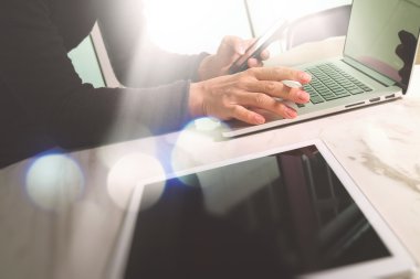 Tasarımcı el ile dizüstü bilgisayar üzerinde mermer masada res çalışıyor.