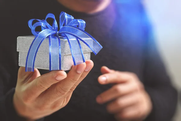 Gift giving, man hand holding a gift box in a gesture of giving.b — стоковое фото