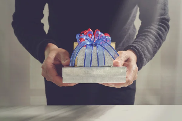 Bescherung, die Hand eines Mannes, der eine Geschenkbox in einer Geste des Schenkens hält. — Stockfoto