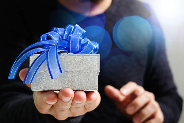 Regalo, mano de hombre sosteniendo una caja de regalo en un gesto de giving.b — Foto de Stock