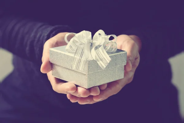 Bescherung, die Hand eines Mannes, der eine Geschenkbox in einer Geste des Schenkens hält. — Stockfoto