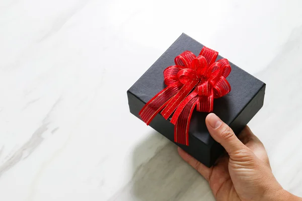 Presente dando, mão de homem segurando uma caixa de presente em um gesto de dar o — Fotografia de Stock