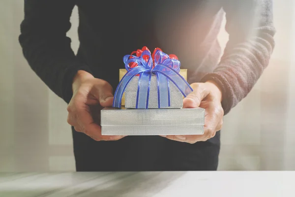 Bescherung, die Hand eines Mannes, der eine Geschenkbox in einer Geste des Schenkens hält. — Stockfoto