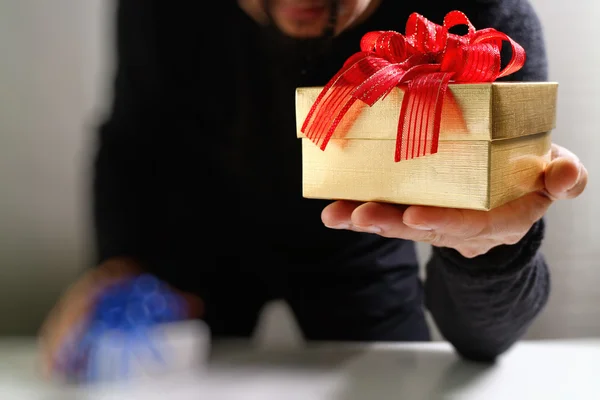 Bescherung, die Hand eines Mannes, der eine Geschenkbox in einer Geste des Schenkens hält. — Stockfoto