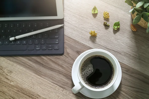 Koffiekopje en digitale tabel dock slimme toetsenbord, vaas bloem haar — Stockfoto