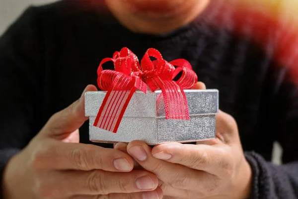 Regalo, mano de hombre sosteniendo una caja de regalo en un gesto de giving.b — Foto de Stock