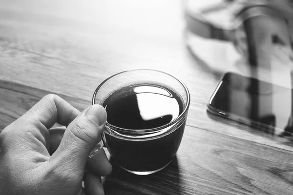 Hand hält Kaffeetasse oder Tee und VoIP-Headset, Smartphone eingeschaltet — Stockfoto
