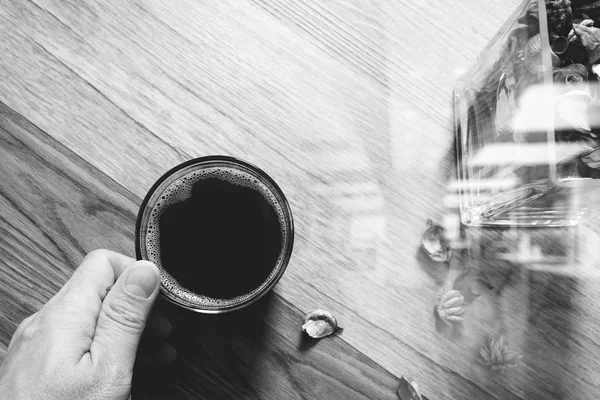 Mão segurando xícara de café ou chá, vaso de vidro ervas de flores secas, em — Fotografia de Stock