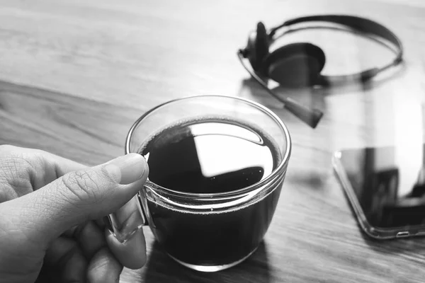 Ręka trzyma Coffee cup lub herbaty i voip zestaw słuchawkowy, inteligentny telefon na w — Zdjęcie stockowe