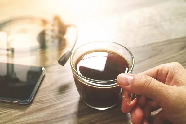 Hand holding Coffee cup or tea and voip headset,smart phone on w — Stock Photo, Image