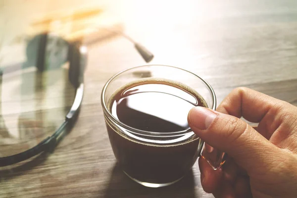 Mão segurando xícara de café ou chá e fone de ouvido voip, livro memorando sobre woo — Fotografia de Stock