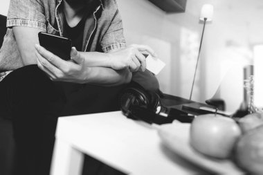 genç adam akıllı telefon l ile hattan alışveriş kanepe üzerinde oturuyor