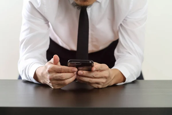 Primer plano del empresario que trabaja con el teléfono inteligente en el escritorio de madera — Foto de Stock