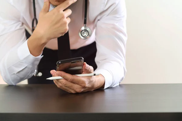 Primer plano del médico inteligente que trabaja con el teléfono inteligente y st — Foto de Stock