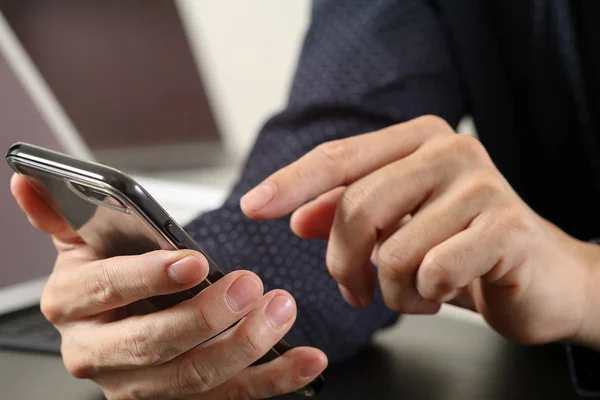 Крупним планом ділова рука, що працює з мобільним телефоном і лапто — стокове фото