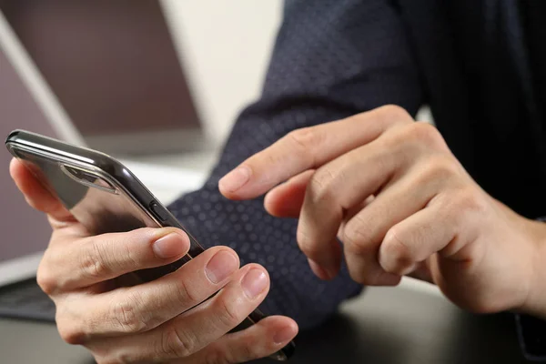 Primer plano de la mano del hombre de negocios que trabaja con el teléfono móvil y lapto — Foto de Stock