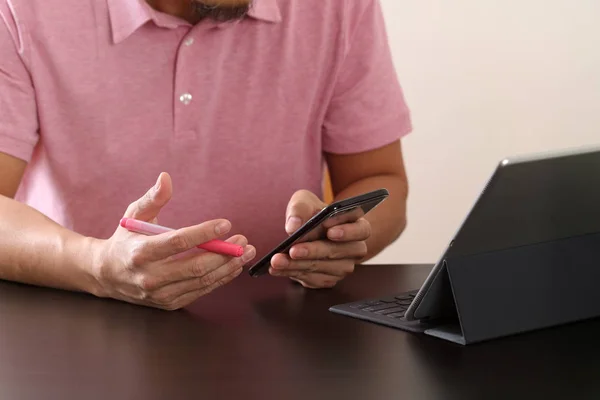 Geschäftsmann im rosafarbenen T-Shirt arbeitet mit Smartphone und Digitalkamera — Stockfoto