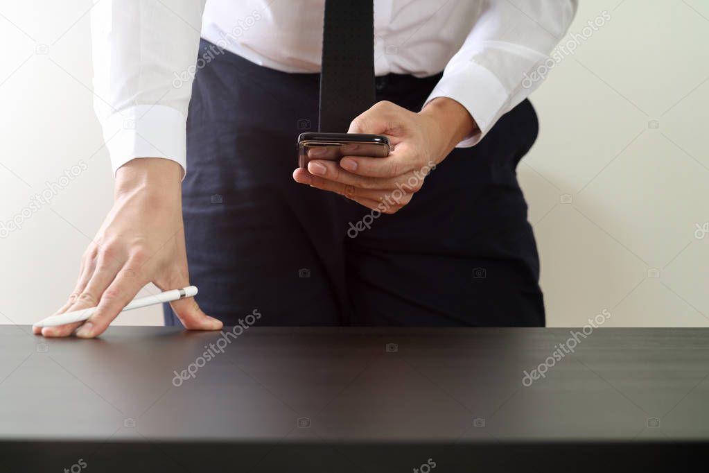 close up of businessman working with smart phone on wooden desk 
