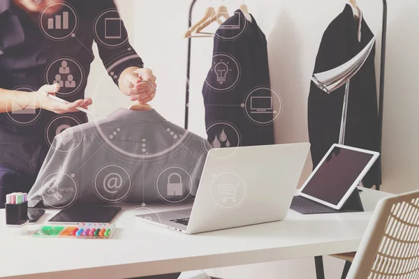 Модельер держит рубашку и использует ноутбук с цифровой вкладкой — стоковое фото