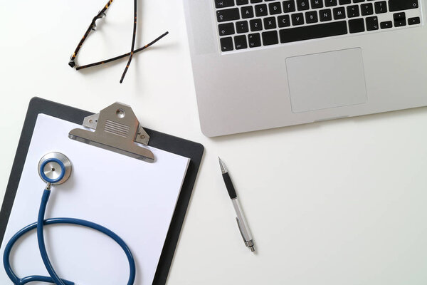 blank stethoscope and gray clipboard and eyeglasses and laptop c