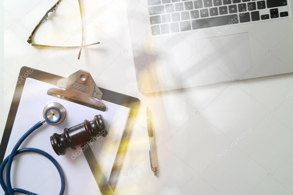 Dark Gavel With Medical Stethoscope near Laptop on white desk In
