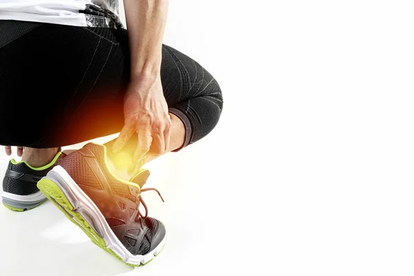 Спортсмен-бегун держит лодыжку от боли сломанным скрученным суставом. — стоковое фото