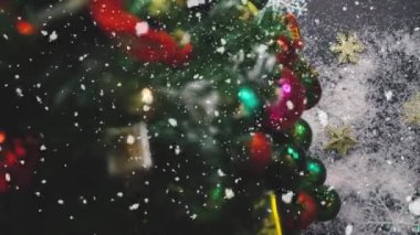 Tebrik sezon kavramı. Noel ağacı ve süslemeleri ile el ayarı sunar ve masada beyaz tahta yukarıdan yağan kar 4 k (Uhd süsler)