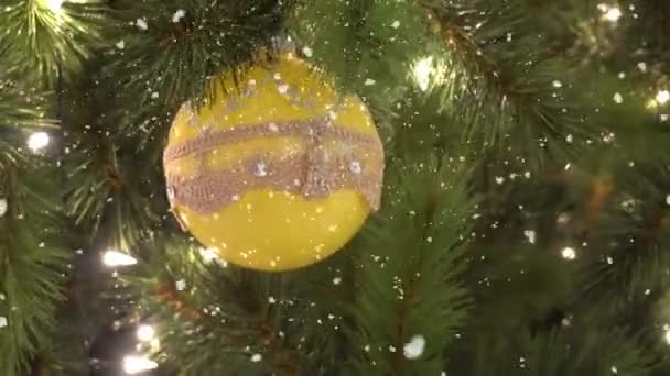 Salutations Concept de saison. Prise de vue à la carabine d'ornements sur un grand sapin de Noël avec lumière décorative et neige tombante en 4k (UHD )