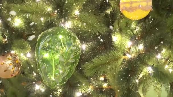 Salutations Concept de saison. Prise de vue à la carabine d'ornements sur un grand sapin de Noël avec lumière décorative et neige tombante en 4k (UHD )