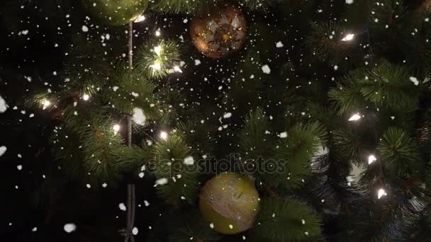 Salutations Concept de saison. Prise de vue à la carabine d'ornements sur un grand sapin de Noël avec lumière décorative et neige tombante en 4k (UHD )