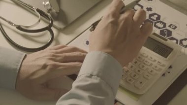 Sağlık görünümünü maliyeti ve kavram ücretleri. Ağır çekimde modern hastanede tıbbi masrafları için bir hesap makinesi akıllı doktor el kullanılır