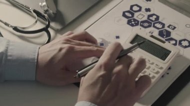 Sağlık görünümünü maliyeti ve kavram ücretleri. Ağır çekimde modern hastanede tıbbi masrafları için bir hesap makinesi akıllı doktor el kullanılır