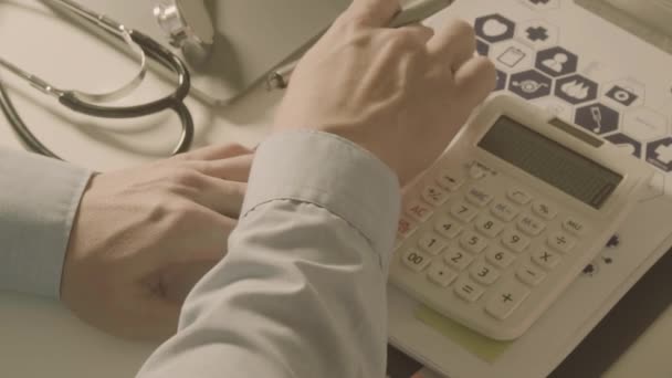 ヘルスケアのビューの上の費用し 料金の概念 スマート ドクターの手がスローモーションで近代的な病院での医療費のため電卓を使用 — ストック動画