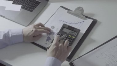 İşadamı, maliyet, hesap makinesi ve modern ofisteki cep telefonlu dizüstü bilgisayarlar hakkında finansman ile çalışıyor.