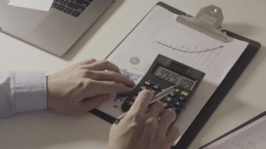 İşadamı, maliyet, hesap makinesi ve modern ofisteki cep telefonlu dizüstü bilgisayarlar hakkında finansman ile çalışıyor.