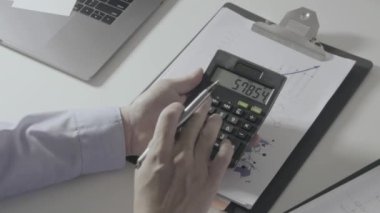 İşadamı, maliyet, hesap makinesi ve modern ofisteki cep telefonlu dizüstü bilgisayarlar hakkında finansman ile çalışıyor.