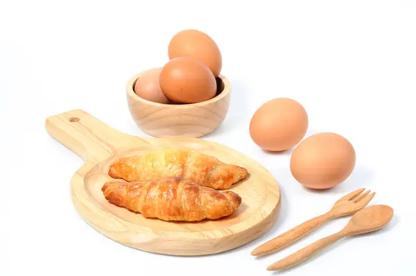 Двойные круассаны и свежие яйца с деревянной посудой — стоковое фото