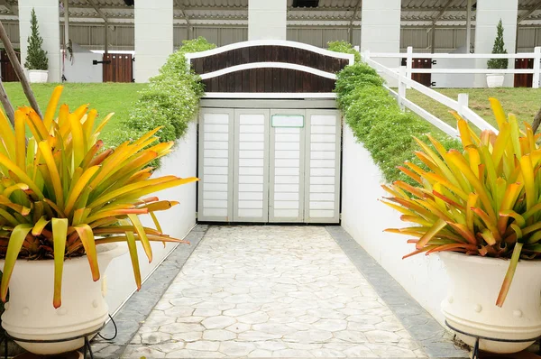 Double big flowerpot on walkway in front of wooden stable door — Stock Photo, Image