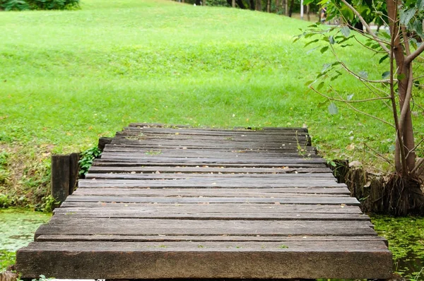 Wooden bridge across small lake in park — Stock Photo, Image