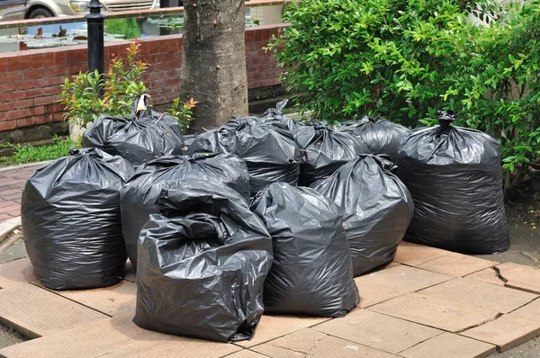 Högen av svart plast soppåsar på marken — Stockfoto