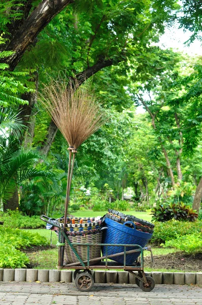 O carrinho usado contém cesta de plástico e vassoura longa na jardinagem — Fotografia de Stock