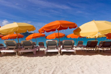 Renkli sandalye ve şemsiye üzerinde beyaz kum Karayip COA'ları