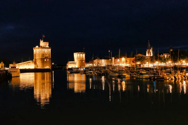 La Rochelle old port (Vieux Port) lit up at night, showing Tour Saint Nicholas (on the left) and Tour de la Chaine (on the right) guarding the entrance to the harbour