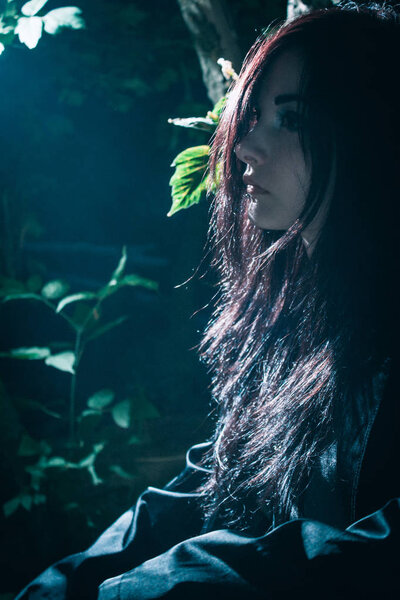 Young gothic asian girl posing in a forest