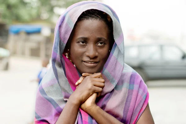 This smiling young veiled woman praying hands clasped.