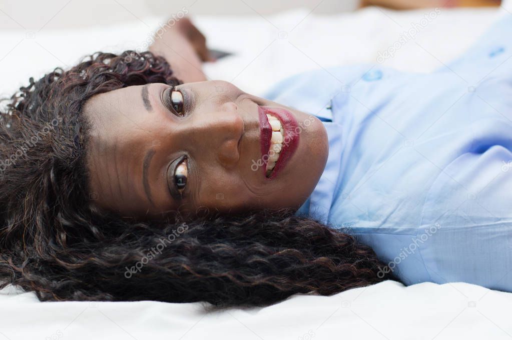 smiling young woman lying down and looking at the camera.