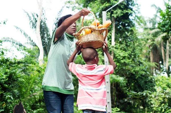 Mom puts the food basket on the head of his son.