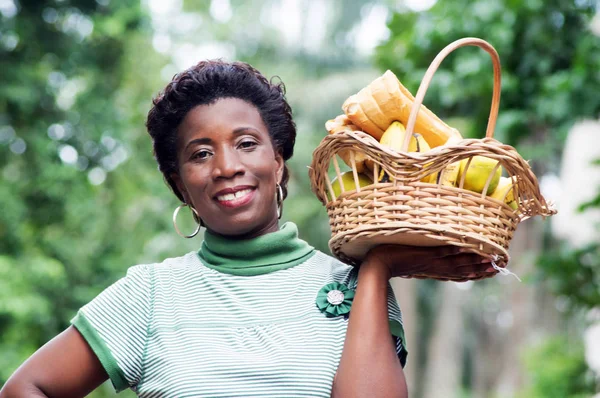 Joven sonriente sosteniendo una cesta de frutas . —  Fotos de Stock