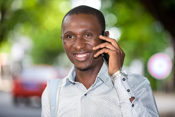 Крупним планом молодий африканський чоловік з мобільним телефоном, щасливий . — стокове фото